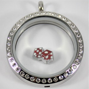 May include: Silver locket necklace with a clear glass insert and a silver charm of two red dice with white dots. The locket is surrounded by a row of clear crystals.
