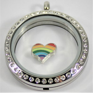 May include: Silver locket necklace with a clear glass insert and a rainbow heart charm. The locket is decorated with clear rhinestones around the edge.