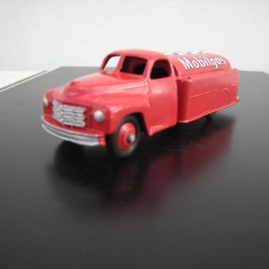 Può includere: Camioncino giocattolo rosso con un logo "Mobilgas" bianco sul lato. Il camioncino ha una cisterna sul retro ed è fatto di metallo.