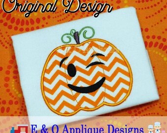 May include: A white t-shirt with an orange and white pumpkin applique. The pumpkin has a winking smiley face. The text "Original Design" is above the pumpkin and "E & O Applique Designs" is below the pumpkin.