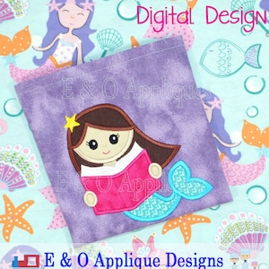 May include: Purple fabric with a design of a mermaid reading a book. The mermaid has brown hair, a pink tail, and a star on her head. The fabric has a tie-dye effect. The text "E & O Applique Designs" is at the bottom of the fabric.