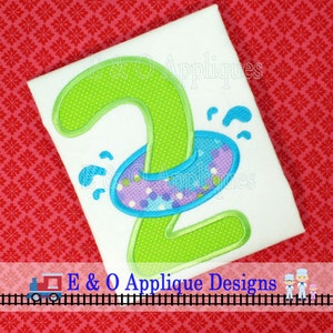 May include: Green number two with a purple and blue life preserver on top. The number two is on a white t-shirt. E & O Applique Designs is written below the number two.