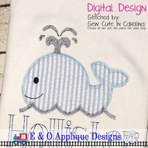 May include: A blue whale applique with a water spout above it. The whale is stitched with a blue and white striped fabric. The text "E & O Applique Designs" is below the whale.