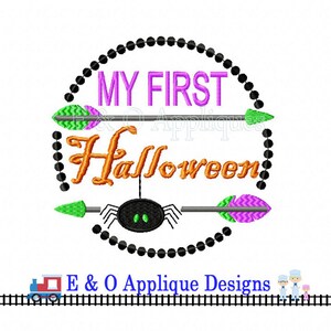 May include: Embroidered design featuring a black spider with green eyes, a purple and green arrow, and the text "My First Halloween" in a black circle with a beaded border.