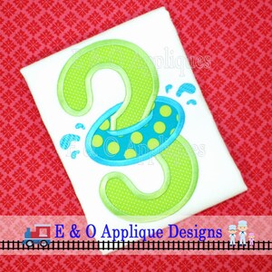 May include: Green number two with a blue and yellow polka dot inner tube around it. The number is on a white shirt. The text "E & O Applique Designs" is at the bottom of the image.