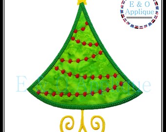 May include: Green felt Christmas tree applique with red felt ornaments and a yellow felt star on top. The tree is standing on a yellow felt stand with two swirls.