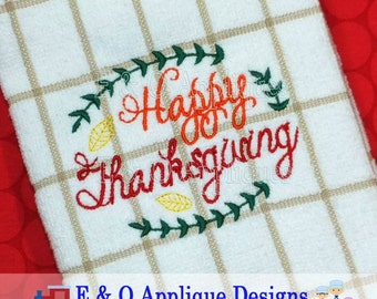 May include: Embroidered kitchen towel with a white background and a brown and white checkered pattern. The towel features a green wreath with yellow leaves and the text "Happy Thanksgiving" in red, orange, and yellow lettering.