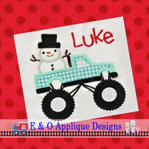 Peut inclure: Un camion monstre vert avec un bonhomme de neige au volant. Le camion a un motif à carreaux et de gros pneus noirs. Le nom "Luke" est brodé au-dessus du camion.