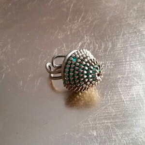 Pu&ograve; includere: Un anello d'argento con una parte superiore a cupola verde e argento. L'anello &egrave; in metallo e ha un design unico.