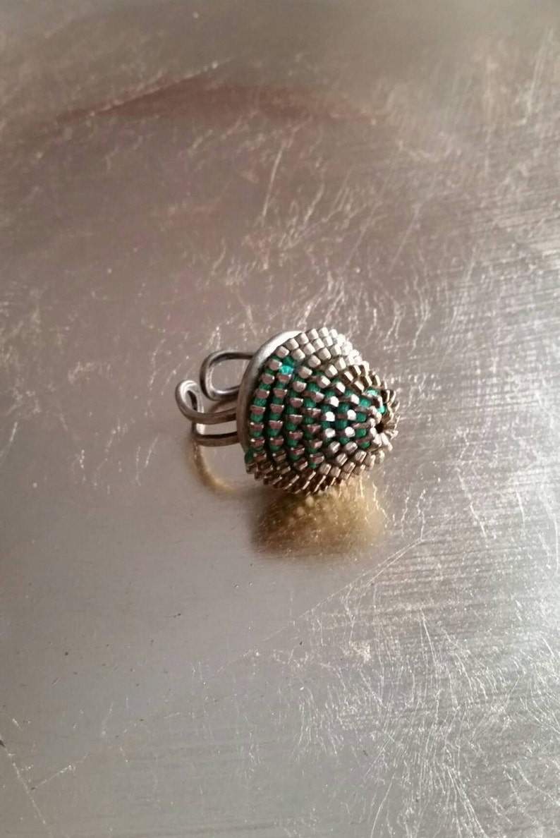 Pu&ograve; includere: Un anello d'argento con una parte superiore a cupola verde e argento. L'anello &egrave; in metallo e ha un design unico.