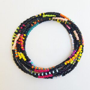 Op de afbeelding: Een kleurrijke kralen tailleketting met zwarte kralen en accenten in roze, oranje, geel, groen en blauw.