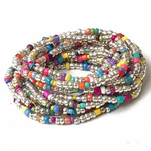 Pode incluir: Um conjunto de pulseiras de contas coloridas com contas prateadas. As pulseiras são feitas com contas pequenas e redondas de várias cores, incluindo rosa, azul, verde, amarelo e laranja.