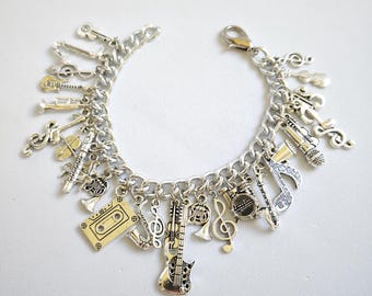 May include: A silver charm bracelet with a variety of music-themed charms, including a guitar, a violin, a trumpet, a saxophone, a music note, and a cassette tape.