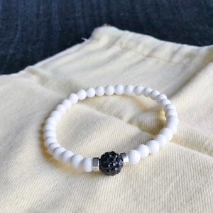 Op de afbeelding: Witte kralen armband met een zwarte strass accent.