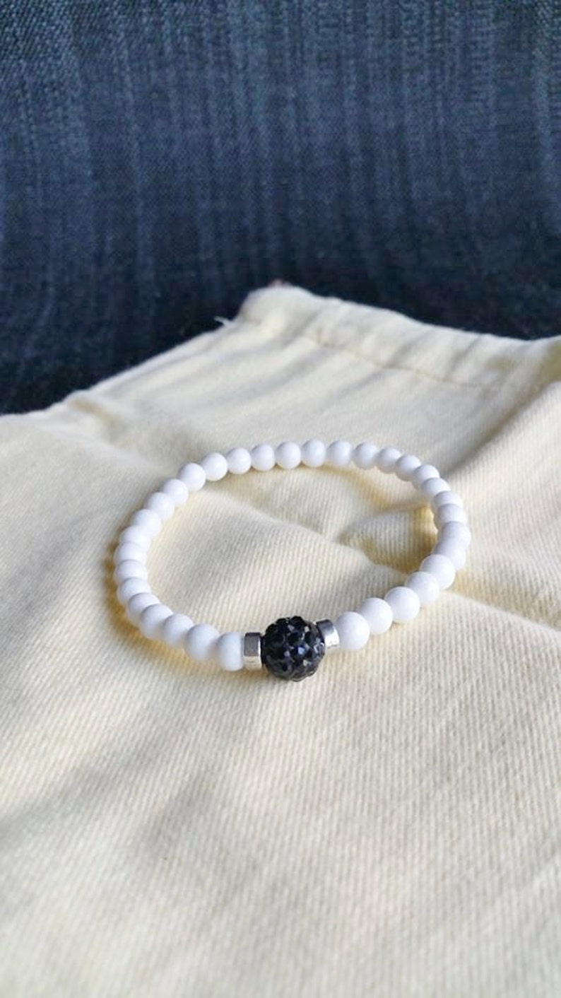 Op de afbeelding: Witte kralen armband met een zwarte strass accent.