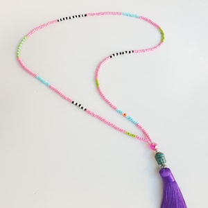 May include: A colorful beaded necklace with a turquoise Buddha pendant and a purple tassel.