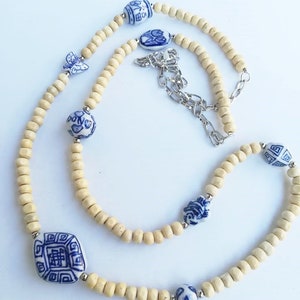 May include: A long necklace made of light brown wooden beads with blue and white porcelain beads featuring Chinese characters and floral designs. The necklace has a silver chain clasp.