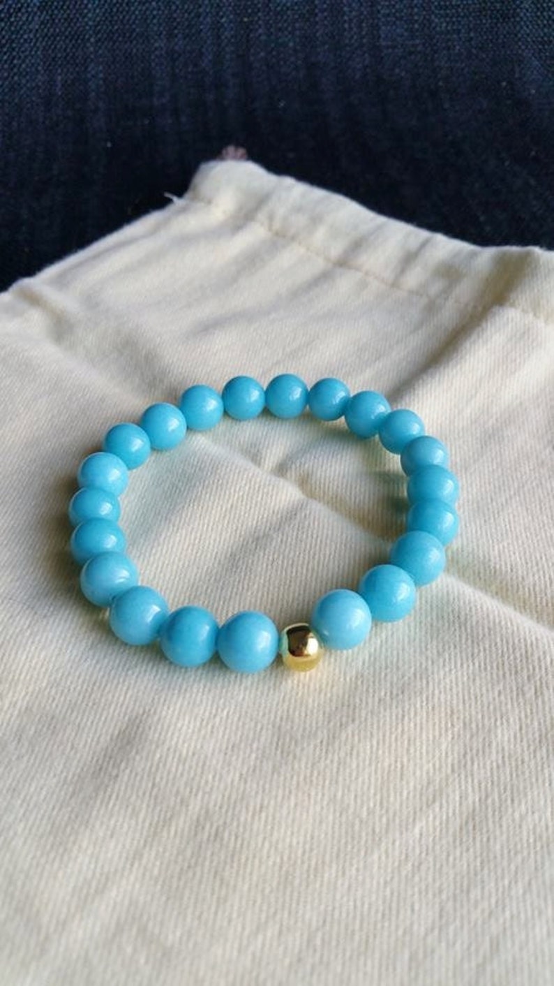 May include: A light blue beaded bracelet with a gold bead accent.
