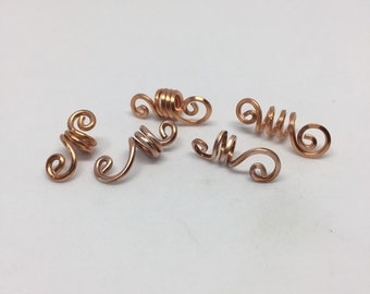 May include: Five copper wire hair beads, each with a unique spiral design. The beads are designed to be used as hair accessories.