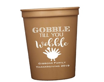 Könnte beinhalten: Ein brauner Plastikbecher mit weißem Text, der "GOBBLE TILL YOU WOBBLE" und eine Truthahn-Grafik zeigt. Darunter steht "GIBBONS FAMILY THANKSGIVING 2019". Der Becher ist konisch und hat einen breiten Rand.