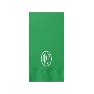 May include: Green paper napkin with a white circle monogram that says "AKT" in a script font.