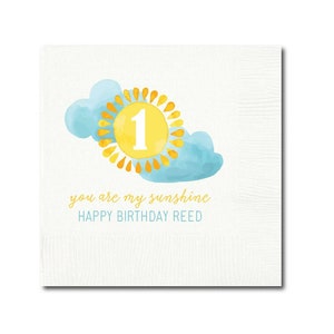 May include: A white card with a yellow sun and blue clouds. The sun has a number 1 in the center. The text reads "You are my sunshine. Happy Birthday Reed."