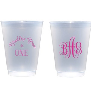 May include: Two frosted plastic cups with pink text. One cup says "Bradley Grace is ONE" and the other cup has the monogram "B G G".