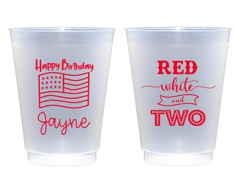 May include: Two red plastic cups with a patriotic theme. One cup says "Happy Birthday Jayne" with an American flag. The other cup says "Red white and two" with a red star design.
