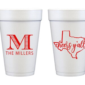 May include: Two white foam cups with red designs. One cup has a red letter "M" with stripes and the text "THE MILLERS". The other cup has a red outline of the state of Texas with the text "cheers y'all".