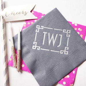 May include: Gray paper napkin with a white monogram "TWJ" in a decorative frame. The napkin is on top of a pink and white polka dot napkin.