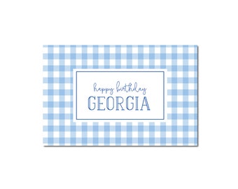 May include: A blue and white gingham background with a white rectangle in the center. The rectangle contains the text "happy birthday GEORGIA" in blue.