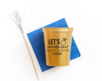 May include: Gold plastic cup with the text "Let's ring in the New Year! Patricia & Wayne 12.31.2020" printed on it.