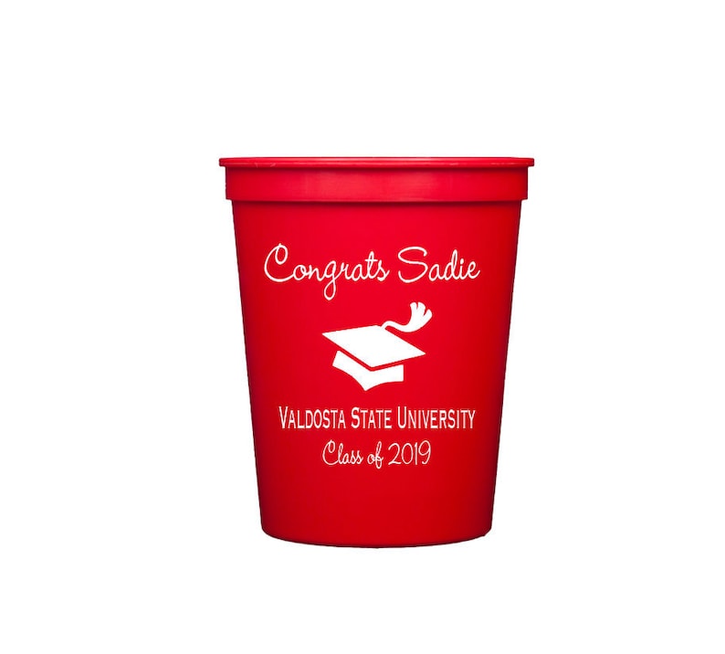 Peut inclure: Gobelet en plastique rouge avec du texte blanc qui dit "Congrats Sadie", "Valdosta State University", et "Class of 2019". Une ic&ocirc;ne de chapeau de graduation blanc est &eacute;galement imprim&eacute;e sur le gobelet.