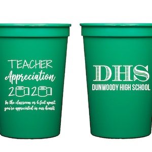 May include: Two green plastic cups with white text. One cup says "Teacher Appreciation 2020" with a toilet paper roll graphic. The other cup says "DHS Dunwoody High School".