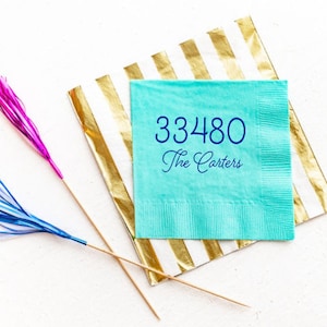 May include: A turquoise blue paper napkin with the text "33480 The Carters" printed in dark blue.
