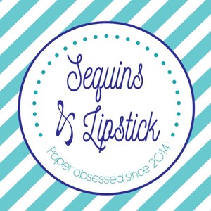 May include: A white circle with a blue border and blue polka dots around the edge. The text "Sequins & Lipstick" is written in a blue cursive font. Below the text is the phrase "Paper obsessed since 2014" in a smaller blue font.