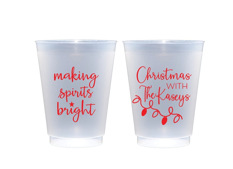May include: Two white plastic cups with red text. One cup says "making spirits bright" with a star. The other cup says "Christmas with The Kaseys" with a string of lights.