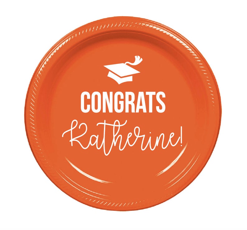 May include: Orange paper plate with a white graduation cap and the text "Congrats Katherine!"