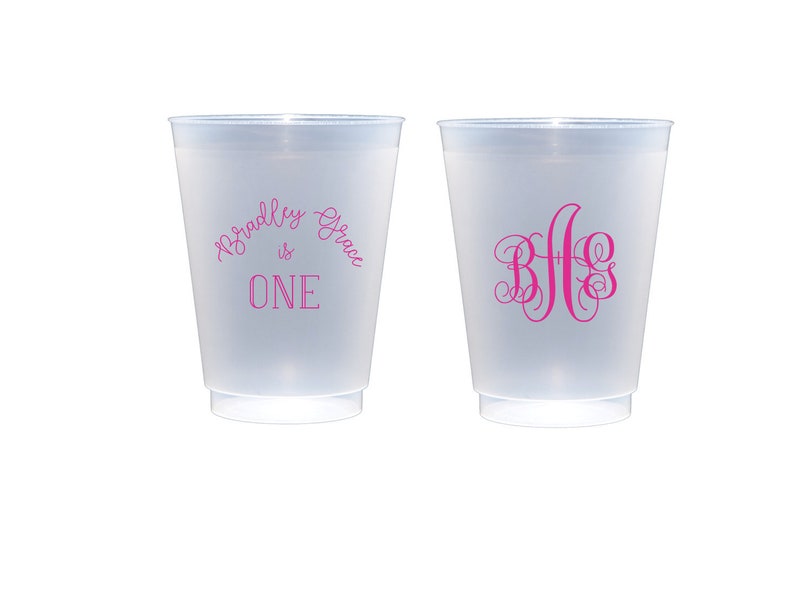 May include: Two frosted plastic cups with pink text. One cup says "Bradley Grace is ONE" and the other cup has the monogram "B G G".