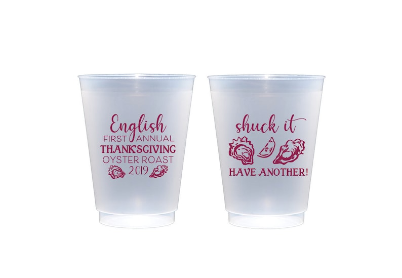 May include: Two white plastic cups with maroon text. The cup on the left says "English First Annual Thanksgiving Oyster Roast 2019" with two oyster shell graphics. The cup on the right says "Shuck it Have Another!" with three oyster shell graphics.