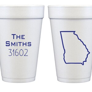 May include: Two white foam cups with blue text and graphics. The cup on the left has the text "THE SMITHS 31602". The cup on the right has an outline of the state of Georgia.