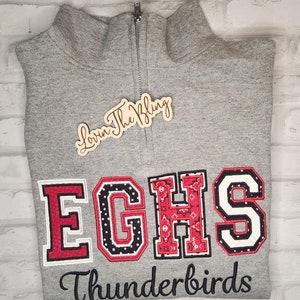 May include: Gray sweatshirt with a zipper and a red, white, and black embroidered "EGHS Thunderbirds" design.