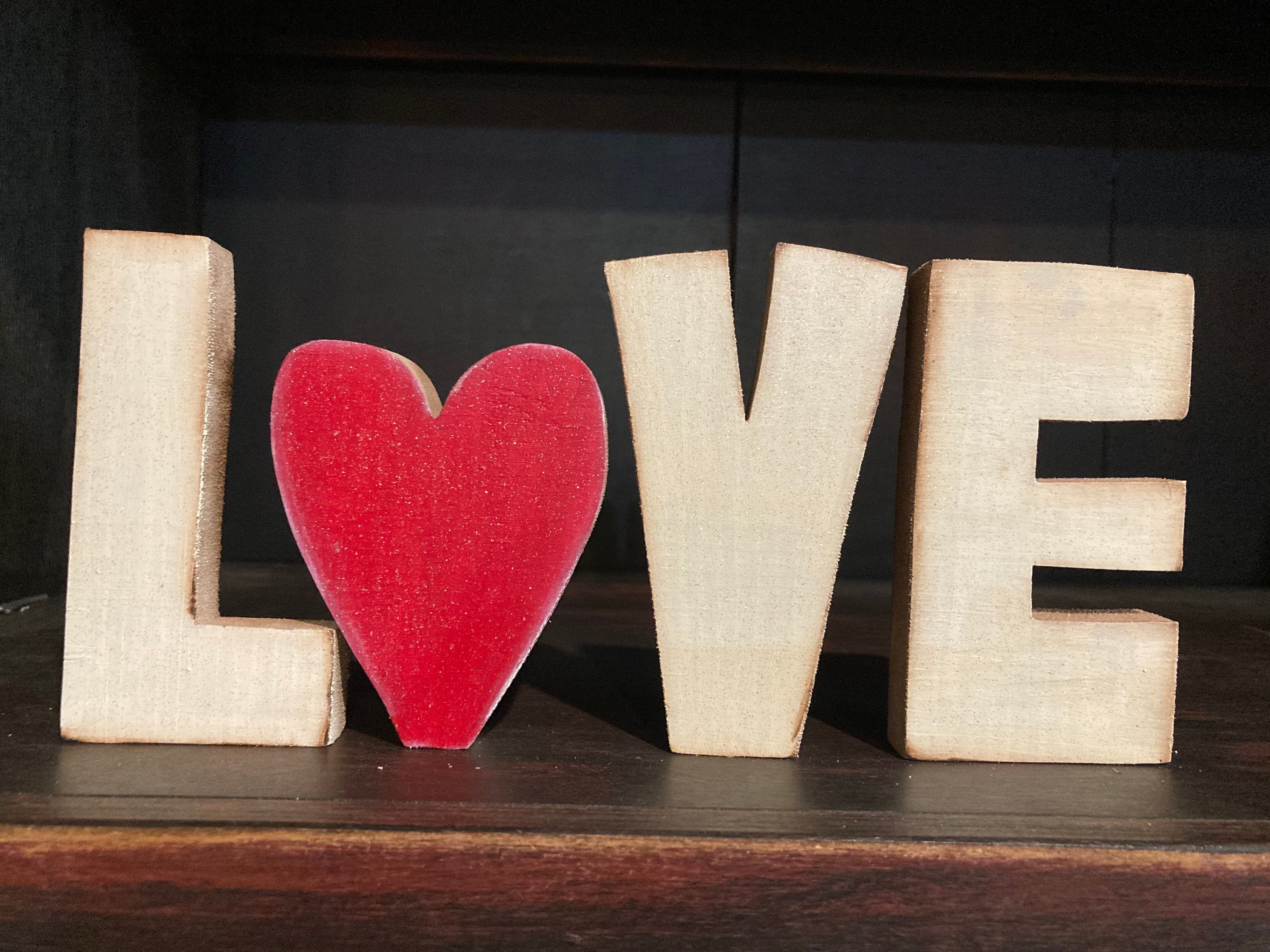 Decorative Letters Forming Word LOVE on Wooden Shelf on White Wall