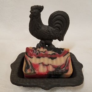 May include: A black cast iron rooster soap dish with a red, white, and black marbled soap bar.