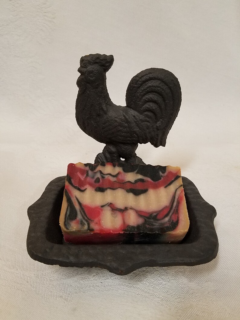 May include: A black cast iron rooster soap dish with a red, white, and black marbled soap bar.