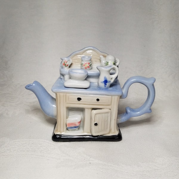 Vintage porcelain teapot shaped like a cupboard