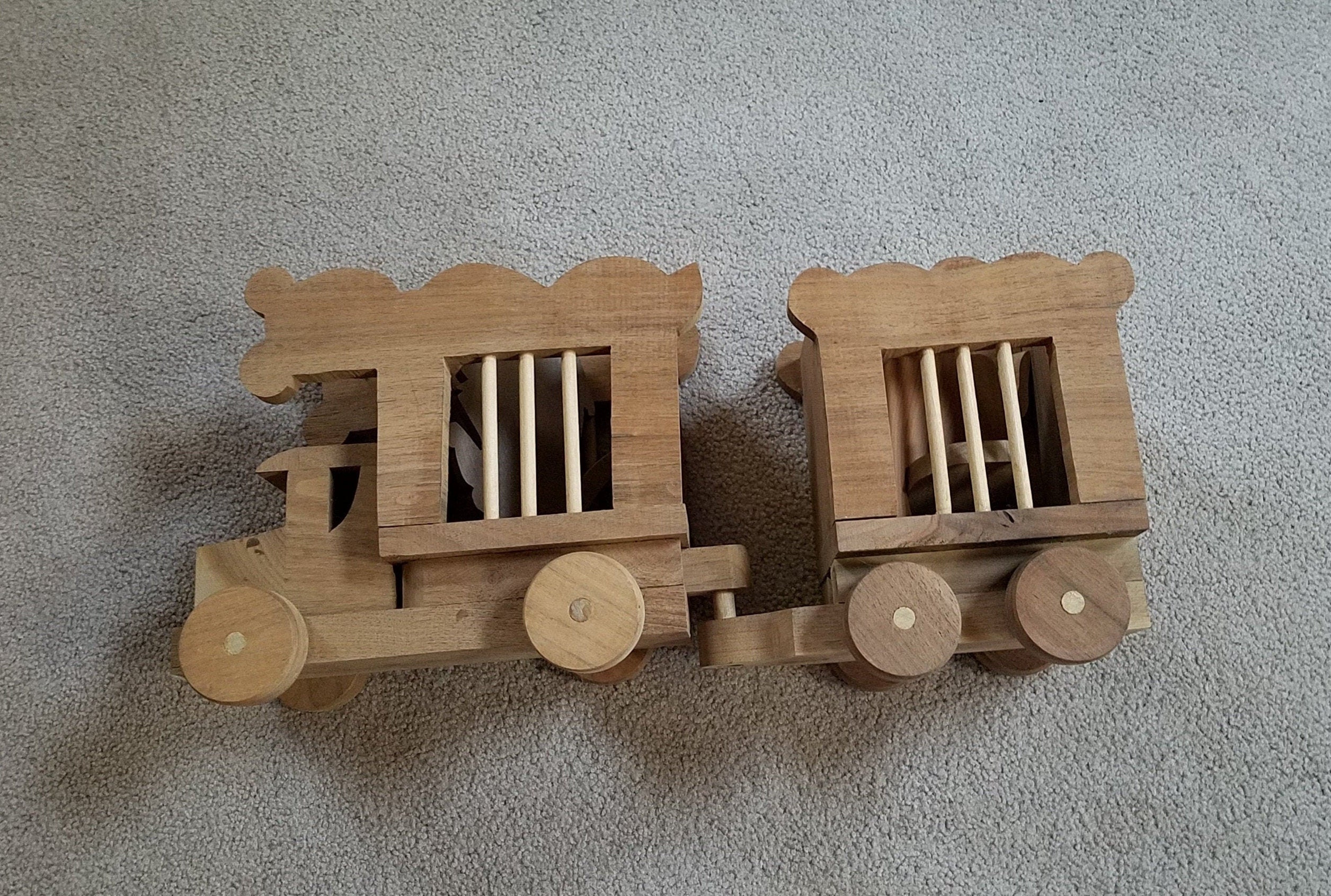 Vintage wooden pull toy of two zoo cars, complete with the wood cut out of a lion, an elephant and a baby elephant
