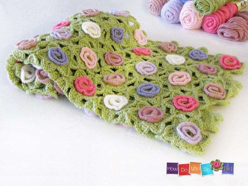 Puede incluir: Una manta de ganchillo verde con un dise&ntilde;o floral. La manta est&aacute; hecha con varios colores de hilo, incluyendo rosa, morado y blanco.
