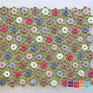 Puede incluir: Una manta de crochet verde con un patr&oacute;n repetitivo de flores de crochet en varios colores, incluyendo rosa, blanco, morado y azul. La manta est&aacute; hecha con una variedad de colores de hilo y es un gran ejemplo de un proyecto de crochet hecho a mano.