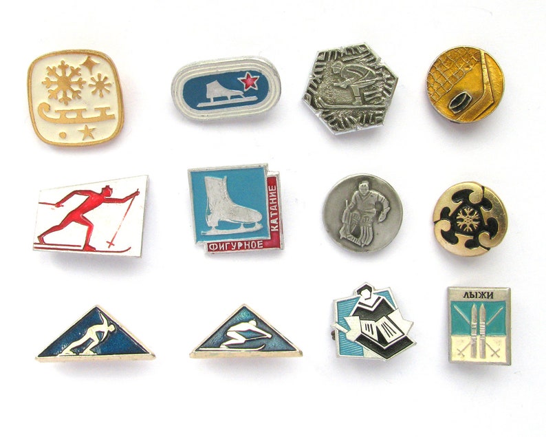 A collection of twelve vintage metal pins featuring various winter sports like skiing, figure skating, and hockey